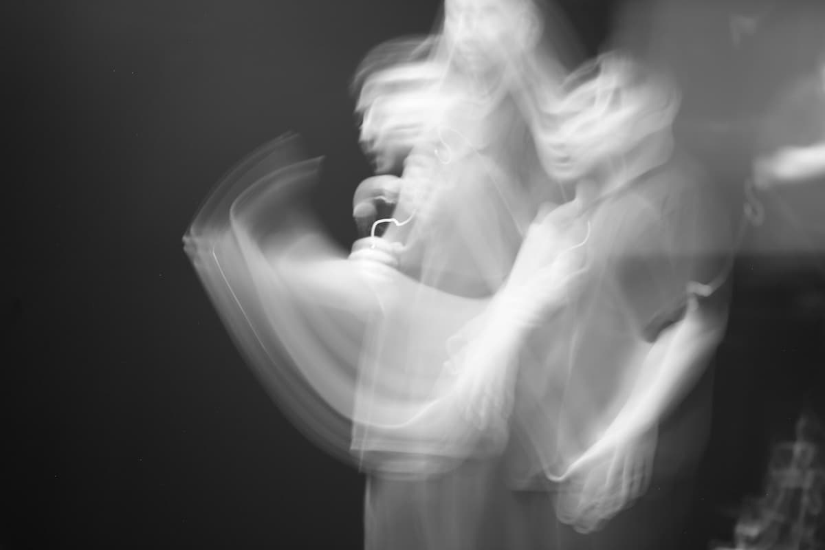 Abstract blurred figures in motion against a dark background